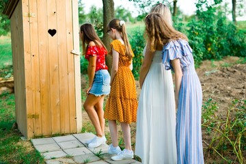 Girls and women waiting for outdoor wooden toilet