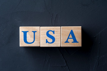 Wooden cubes with word USA on dark table.