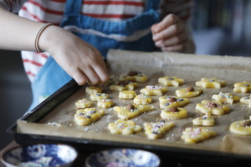 Backblech mit Weihnachtsplätzchen und Kind mit Schürze