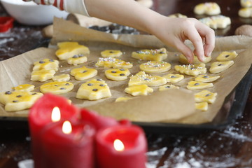 Kinder backen Weihnachtsplätzchen mit Teig, Backblech, Zuckerstreusel, Nüsse, Zutaten, Mehl, Backform, rote Kerze in der Adventszeit an Weihnachten