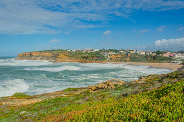 View of the Atlantic ocean, waves, picturesque village in Portugal. Panorama. Windy ocean in sunny...