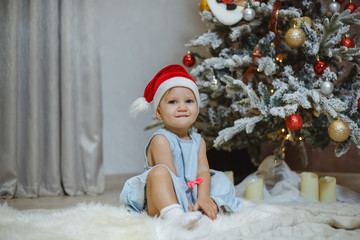 Obraz na płótnie Canvas Little and beautiful girl next to a Christmas tree.
