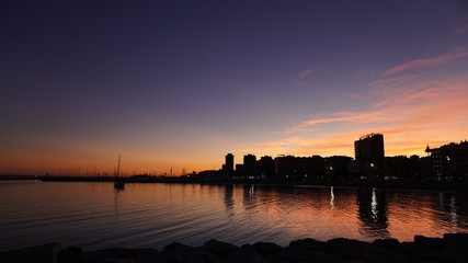 Ciudad con mar en puesta de sol