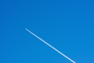 Airplane and inversion trail against a clear blue sky. The concept of travel. Copy space.