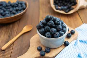 Ripe blueberries in the bowl on the wooden table. Fresh berries for breakfast.
