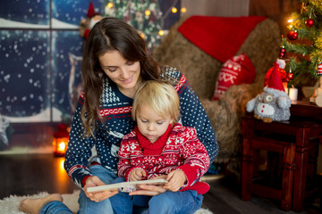 Happy smiling family, mom and boy, reading book at Christmas