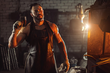 cool caucasian and young blacksmith portrait. forger in work with metal, powerful bodybuilder,...