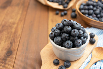 Ripe blueberries in the bowl on the wooden table. Fresh berries for breakfast. Copy space.