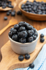 Ripe blueberries in the bowl on the wooden table. Fresh berries for breakfast.