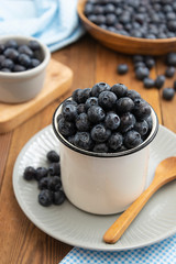 Ripe blueberries in metalic cup on the wooden table. Fresh berries for breakfast. Copy space.