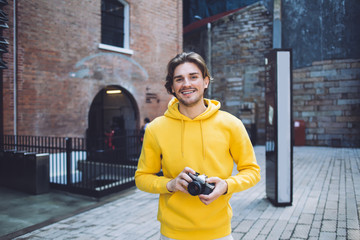 Man with photo camera standing next to brick building