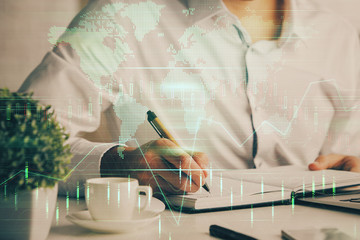 Double exposure of man's hands writing notes of stock market with forex chart.