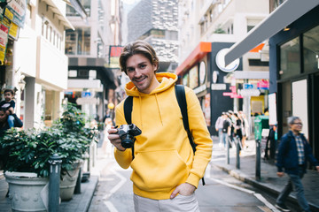 Happy young man holding camera outdoors