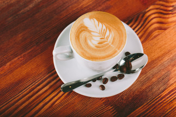 Cup of coffee cappuccino for lefties  with cream wooden background