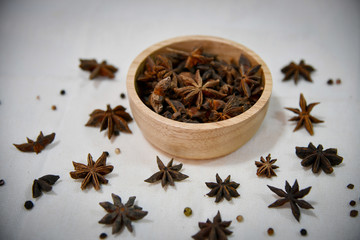 Close up photo of star anise in wooden bowl on white background.