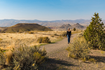 A young brown tourist with gray tufts walks through Painted Hills