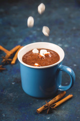 Christmas hot chocolate in a blue cup on a blue background.