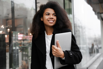 business woman using digital tablet Young beautiful successful African American  woman walking urban street outdoor with laptop computer in hands. Confident worker freelancer natural lifestyle. Candid - obrazy, fototapety, plakaty