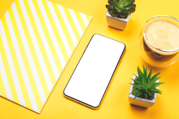 Modern smartphone screen on a yellow desktop.