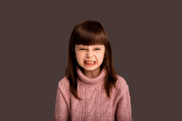 Angry irritable and mischievous little girl, naughty child, yelling at camera and grinning teeth