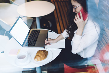 Young casual woman budding specialist searching information about job using devises at cafe