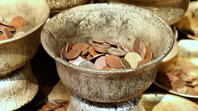 A coins in cups, financial gifts of believers in buddhist temple.
