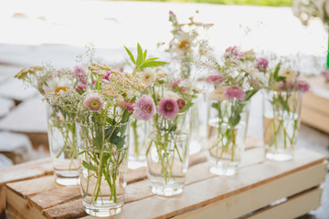 small bouquets in glass vases on a wooden pallet