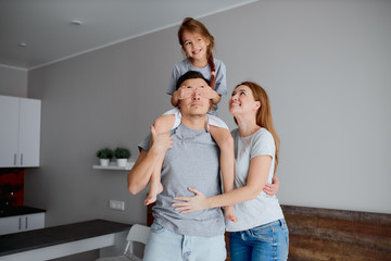 Leisure. young caucasian family stand in bedroom and happy together, smiling and laughing. little girl sit on choulders of handsome strong father, while mother hugging him. love and family concept