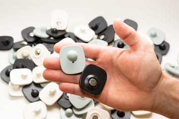 many multi-colored anti-theft sensor on a man’s male hand on a light background