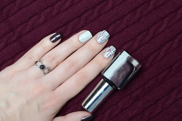 Burgundy wine manicure with geometric pattern with triangles and ring on knitted sweater background