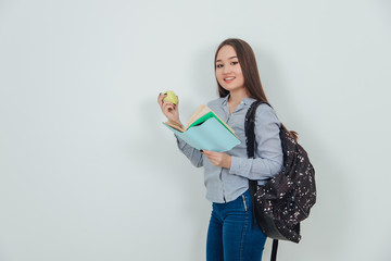Cute young asian girl standing, holding an interesting book and yellow apple, looking at the...