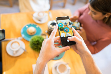 Man Capturing Food Photos On Cellphone In Cafe