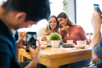 Best Friends Posing While Man Photographing Them At Cafe