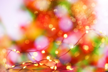 Obraz na płótnie Canvas Abstract blurred photo of garland lights in the foreground and blurred abstract image of a decorated Christmas tree in the background. bright photo.