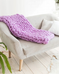 Fototapeta na wymiar A large merino lilac plaid blanket lies on a sofa