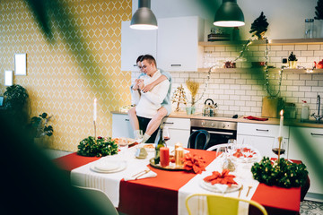 Couple cuddling in kitchen on Christmas eve