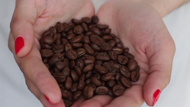 young woman holding handfull of coffee beans