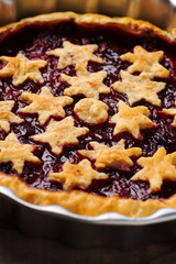 Home baked puff pastry Christmas New years pie torte with plum cinnamon jam filling decorated with stars in rustic baking form. Holiday baking concept