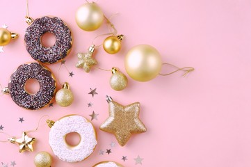 Top view of christmas composition decoration of snowflakes, stars, balls, donuts of golden and white  color on a pink background. Flat lay with copy space for text.