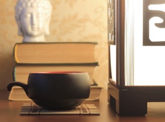 Japanese elements in interior. ceramic cup of tea, books, white head of Buddha