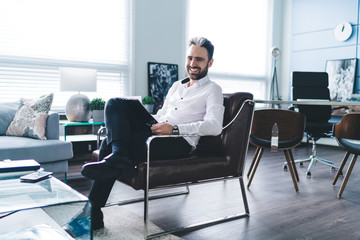 Cheerful businessman lounging on chair in office