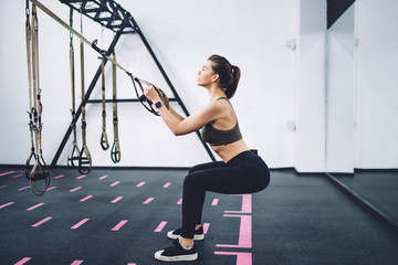 Woman doing squat exercises with TRX straps