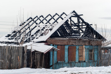 ruins of a burnt log hut in a winter landscape