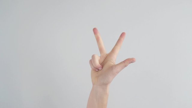 The woman is hand shows fingers one, two, three and squeezes her hand into a fist. Close-up