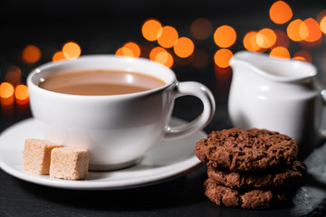 Chocolate cookies, coffee, spices on a background of Christmas lights.