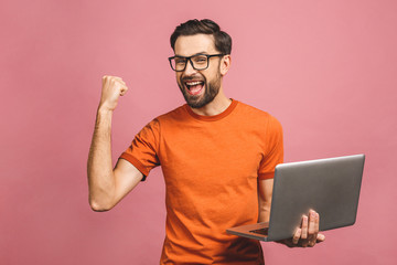 Image of happy excited young man posing isolated over pink background wall using laptop computer...
