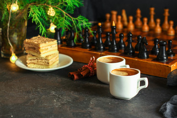 coffee, piece of cake (festive atmosphere, chess, Christmas lights, new year) menu concept. food background. top view. copy space