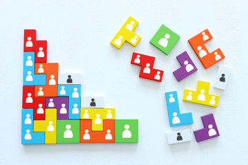 Business concept image of tangram puzzle blocks with people icons over wooden table, human...