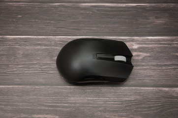 black computer mouse on a wooden background. Close-up.