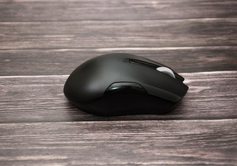 black computer mouse on a wooden background. Close-up.